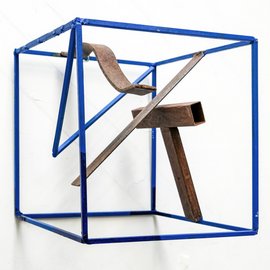 [Translate to English:] Metallskulptur lackiert. Abstrakte Elemente aus rostigem Eisen in blauem Kubus.